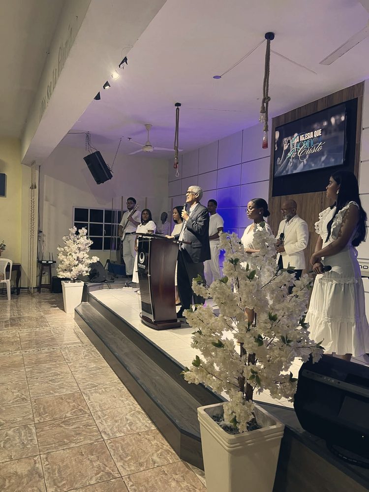 Pastor predicando con el equipo de alabanza en la plataforma